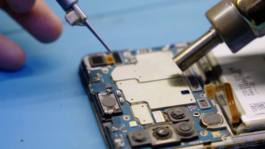 Person using a soldering station on a motherboard
