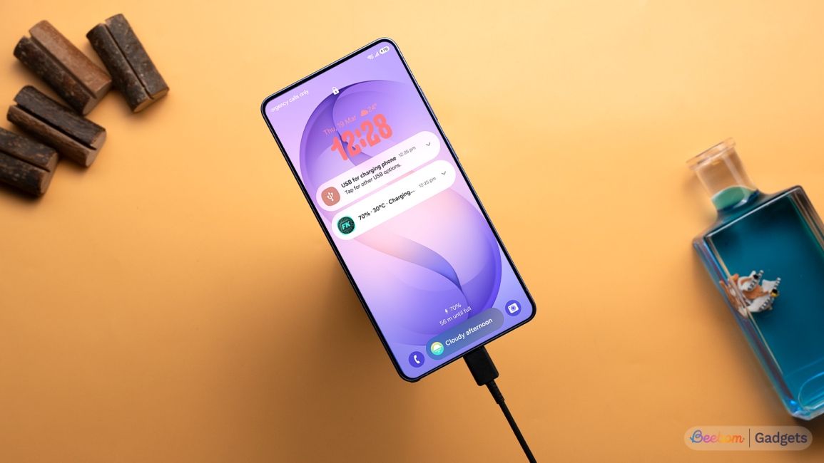 Samsung Galaxy S26 Ultra shown plugged to a charger against an orange background