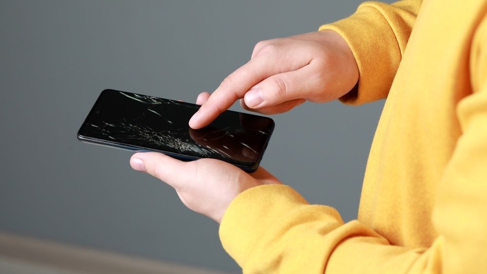 a man holding a phone with broken screen