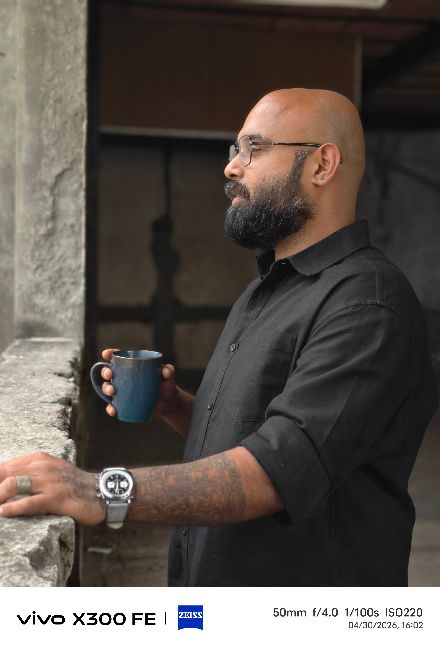 A man sipping on a cup of coffee on a balcony