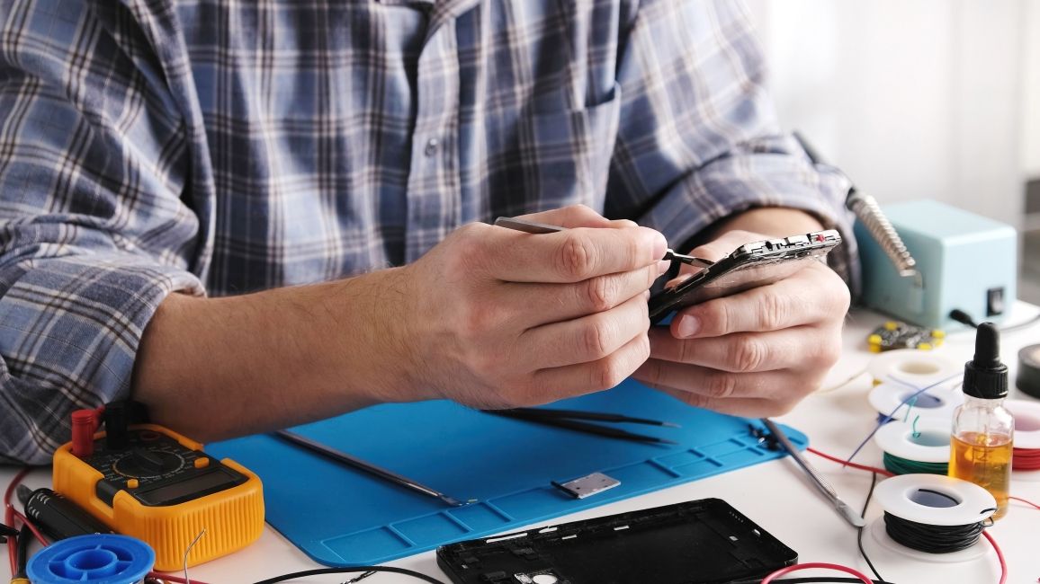 shot of a person repairing a phone with the back side exposed