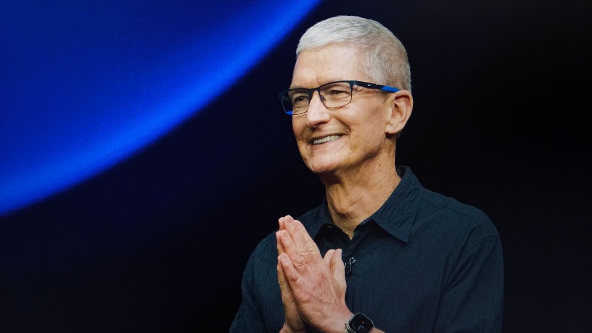 Apple CEO Tim Cook smiling and joining hands as a sign of gratitude