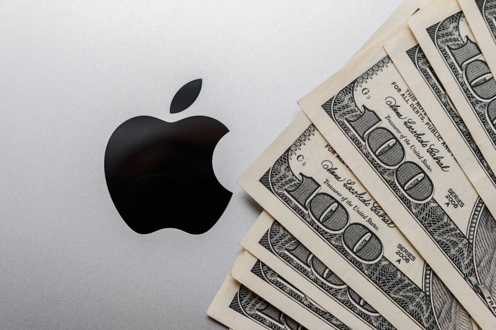 Apple logo on MacBook with money US dollars around stock image
