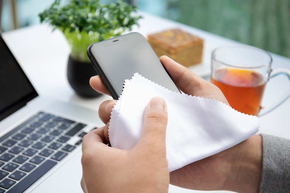 shot of a hold holding an iPhone that's being cleaned with a piece of cloth