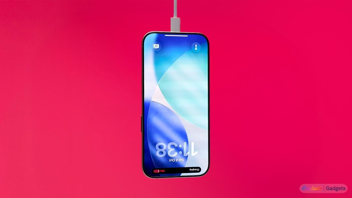 iPhone 17 charging upside down against a red background