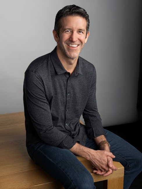apple ceo john ternus sitting on a table and smiling apple ceo john ternus sitting on a table and smiling